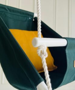 Närbild på mörkgrön babygunga Ambition med gul kudde, handmålad träpinne och Videung-logga.